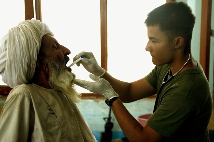 Seaman Oscar Medrano, a corpsman assigned to Task Force 2nd Battalion, 7th Marine Regiment, 1st Marine Division, Combined Joint Task Force Phoenix, examines an Afghan patient during a medical capabilities health cooperative Aug. 24.