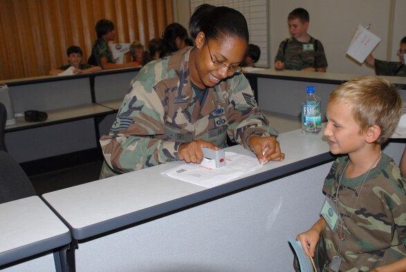 Staff Sgt. Candice Ayers, 15th Logistics Readiness Squadron, stamps the Airmens' orders as they prepare to deploy during Operation Hele On. Operation Hele on provides Hickam’s youngest warriors a glimpse into what their parents go through as they prepare to deploy. (U.S. Air Force Photo/Staff Sgt. Erin Smith) 