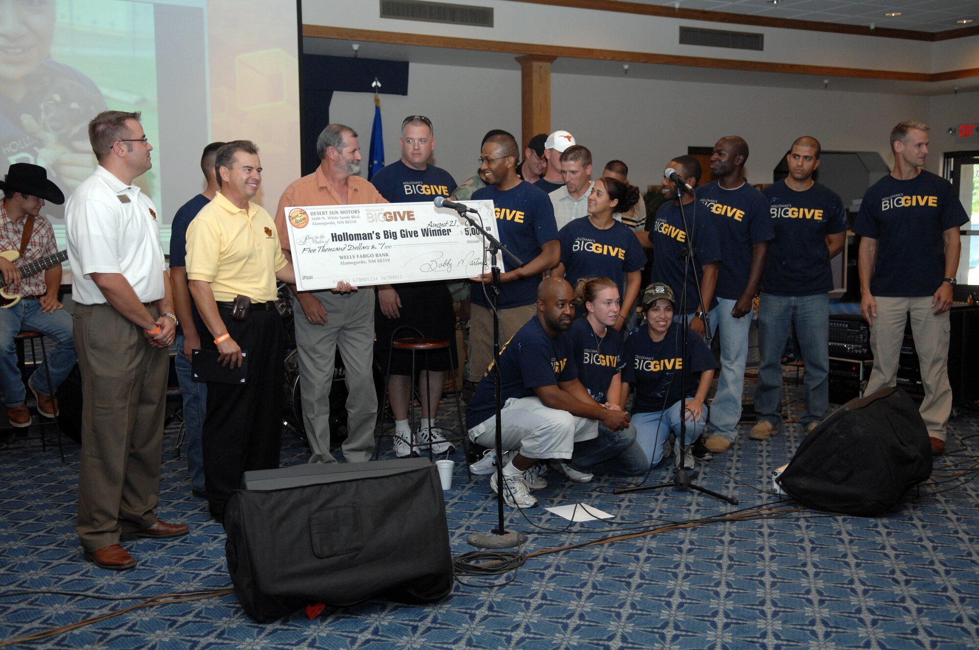 Representatives of Desert Sands Motors of Alamogordo present the Housebusters team with a $5,000 check after they were announced the winners of the Big Give challenge during the after party at the Enlisted Club at Holloman Air Force Base, N.M., August 21. The Housebusters team adopted the Step House, which is a home for recovering alcoholics and addicts. They brought electricity to rooms that were otherwise dark, laid new flooring in several rooms and hallways, and painted and decorated the home. The Housebusters, led by Master Sgt. Timothy Miles, 49th Civil Engineer Squadron, also won the People?s Choice award and were presented with a $500 check from Otero Federal Credit Union. (U.S. Air Force photo/Airman Sondra M. Wieseler)