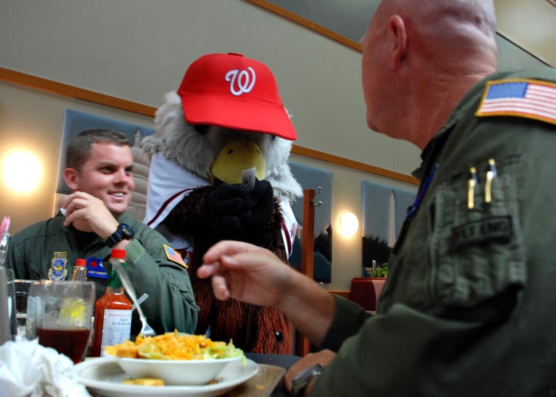 The Washington D.C. Nationals baseball team mascot Screech hands out free tickets to Airmen at the Freedom Hall Dining Facitlity Aug. 26 for the Nationals' game against the Braves Friday.
