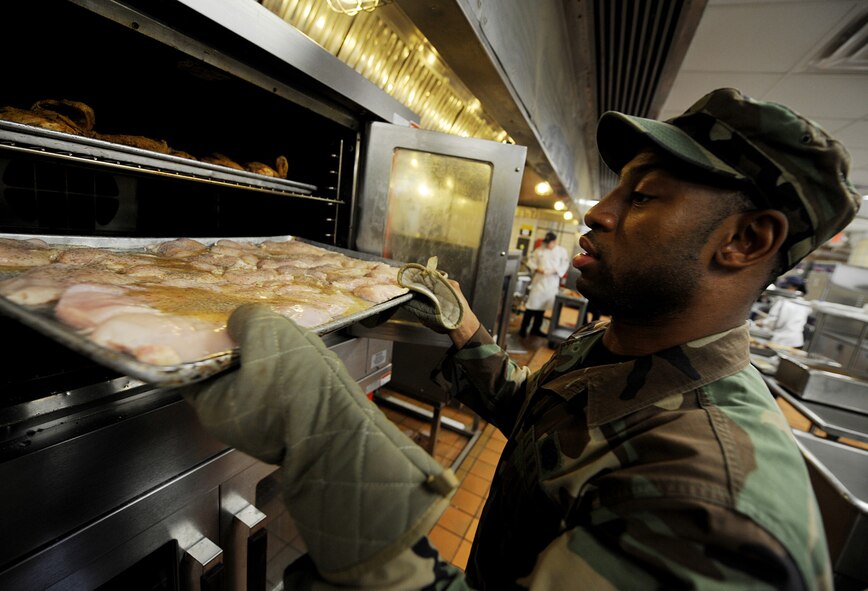 MOODY AIR FORCE BASE, Ga. -- Airman 1st Class Lamar Heyward, 23rd Force Support Squadron food specialist, puts chicken breasts into an oven here Aug. 20. The Georgia Pines Dining Facility serves an average of three to four hundred customers during lunch hours. (U.S. Air Force photo by Senior Airman Gina Chiaverotti)
