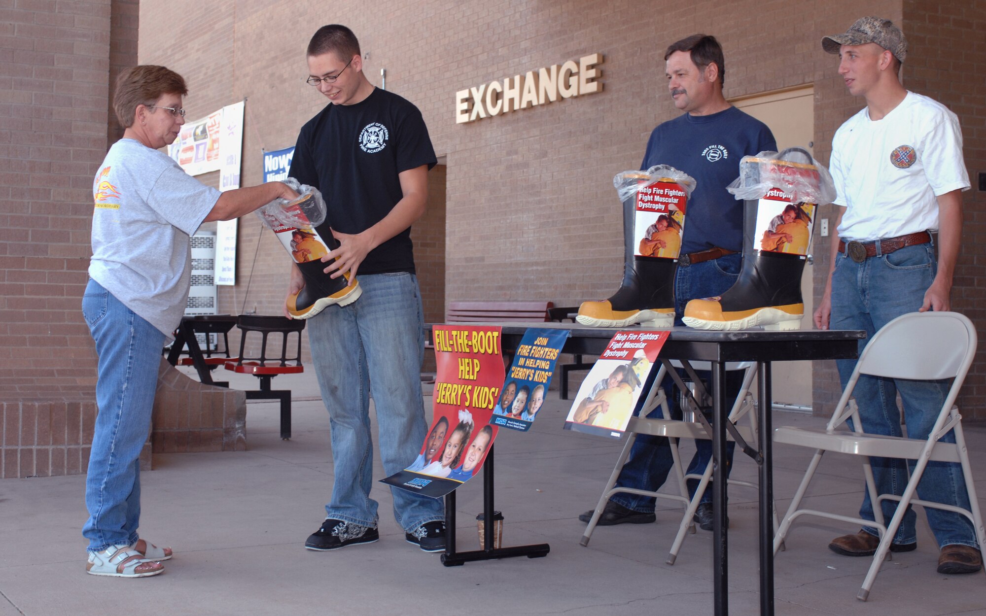 CANNON AIR FORCE BASE, N.M.- Mrs. Pam Newheart, 27th Special Operations Services Squadron, places a donation in a firefighter's boot held by Airman 1st Class Erik Richmond, 27th Special Operations Civil Engineer Squadron, as Mr. Bruce Ford, 27th SOCES, and Airman 1st Class Wesley Poppel, 27th SOCES, look on. The 27th SOCES raised money at the Shopette and the Base Exchange on Aug. 23 for Jerry Kids. The donations raised will benefit children around the world suffering from muscular dystrophy. (U.S. Air Force photo/Airman 1st Class James R. Bell)