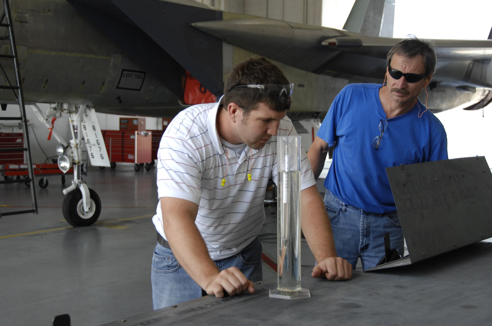 Ryan Mead, left, an F-15 fuels engineer from the 830th Aircraft Sustainment Group, Robins Air Force Base, Ga., and Daryl Fortenberry, an aircraft mechanic, 561st Aircraft Maintenance Squadron, conduct fuel density testing to ensure the proper weight for the aircraft's fuel requirements. The test was accomplished prior to the first test flight of a fighter aircraft using synthetic fuel. (U.S. Air Force photo/Claude Lazarro)