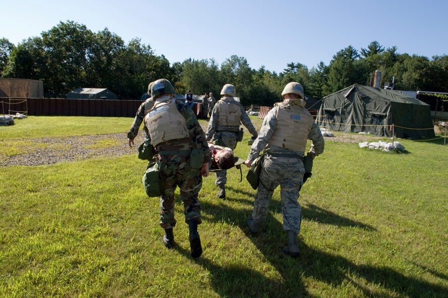 HANSCOM AFB, MASS. -- Airmen practice transporting a wounded comrade during a base readiness exercise here, Aug. 21. During the exercise, Airmen from Hanscom demonstrated their abilities to survive and operate in a combat environment. Readiness exercises help Airmen prepare for deployment. (U.S. Air Force photo by Rick Berry)