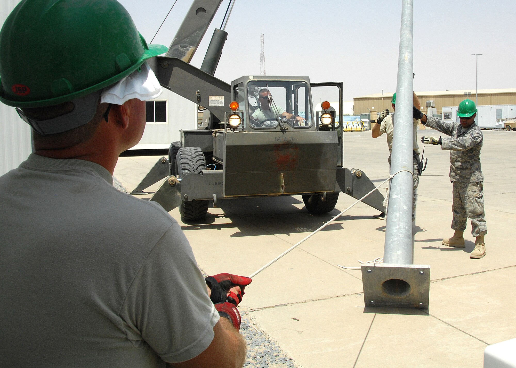 SOUTHWEST ASIA -- Staff Sgt. Ricky Clark steadies a support cable while Master Sgt. Steven Gaskill (left) and Senior Airman Jose Lozadacosme, all assigned to the 386th Expeditionary Civil Engineer Squadron, help stabilize a light pole while it's being secured to its permanent base on Aug. 23 at an air base in Southwest Asia. The 386th ECES installed four new light poles on the Republic of Korea Air Force compound because of previous wind damage to the poles. The installation was a joint effort between U.S. and Korean Airmen. Sergeant Clark is deployed from the New Jersey Air National Guard, and Sergeant Gaskill is deployed from the New Jersey Air National Guard. Airman Lozadacosme is deployed from the Air National Guard in Puerto Rico. (U.S. Air Force photo/Tech. Sgt. Raheem Moore)