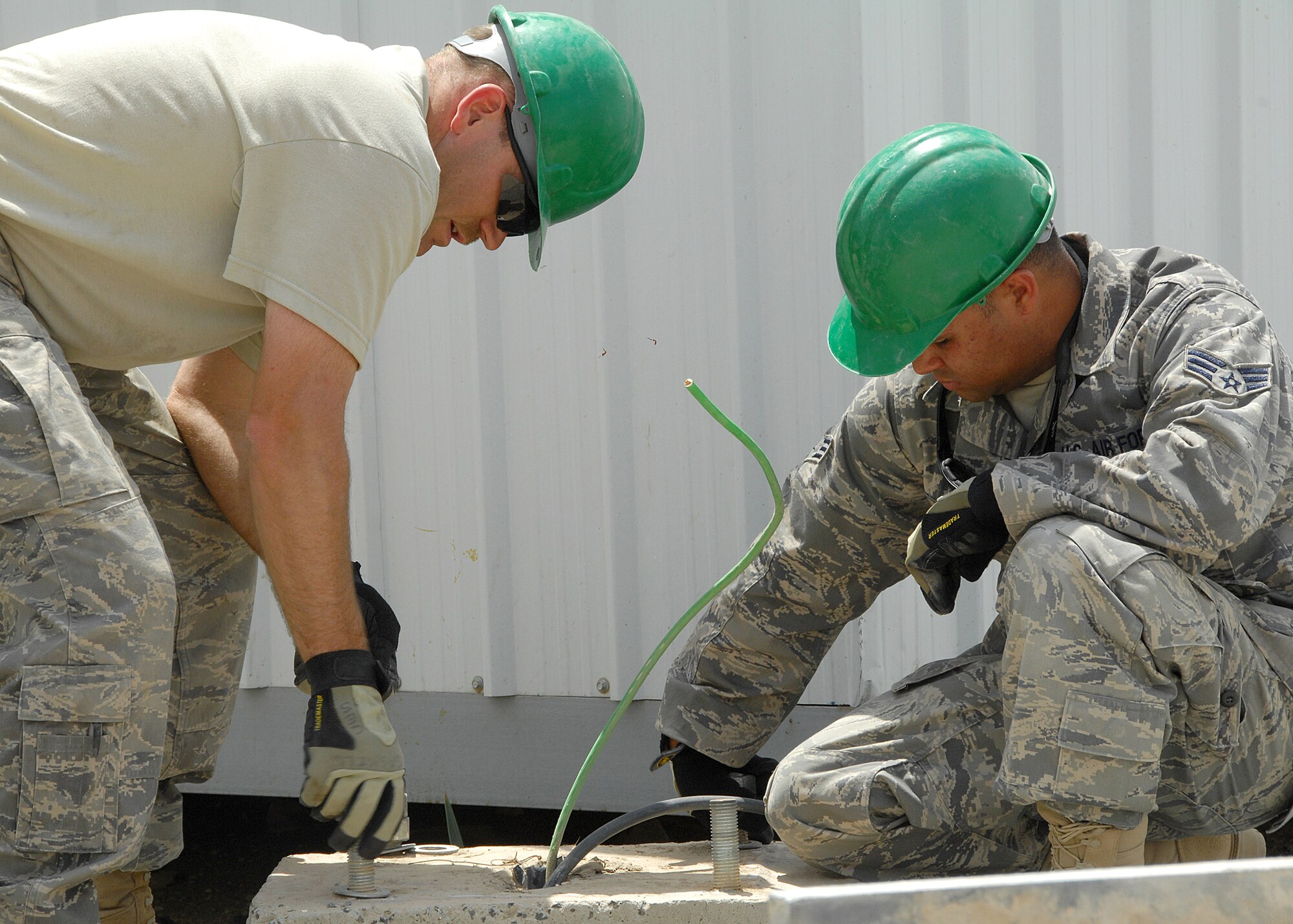 SOUTHWEST ASIA -- Staff Sgt. Ricky Clark and Senior Airman Jose Lozadacosme, both assigned to the 386th Expeditionary Civil Engineer Squadron, tighten down bolts on the base of a light pole on Aug. 23 at an air base in Southwest Asia. The 386th ECES installed four new light poles on the Republic of Korea Air Force compound because of previous wind damage to their poles. The installation was a joint effort between U.S. and Korean Airmen. Sergeant Clark is deployed from the New Jersey Air National Guard. Airman Lozadacosme is deployed from the Puerto Rico Air National Guard. (U.S. Air Force photo/Tech. Sgt. Raheem Moore)