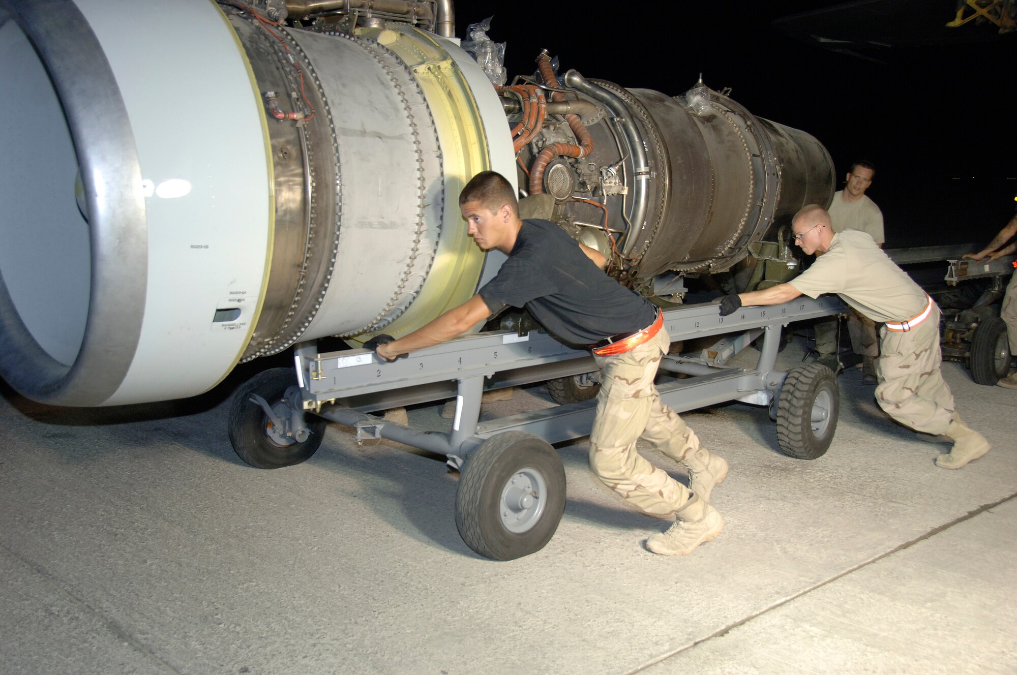 SOUTHWEST ASIA--(left to right) Airman 1st Class Seth Hammont, Senior Airman Robert West from the 380th Expeditionary Aircraft Maintenance Squadron pushes an E-3 Sentry engine while Senior Airman Rodney Poe, also from the 380th EAMXS guides it out here Aug. 24.  They are replacing #4 Engine due to the fact that it surpassed allowable exhaust temperature limits. This was the 6th engine change in 120 days. The normal fix time to remove and replace an E-3 engine is 18 hours. The technicians here have sliced that time in more then half. Their average time to change an engine and replace the aircraft to flyable condition here is 8 1/2 hours. They are all deployed from the 552nd Aircraft Maintenance Squadron, Tinker Air Force Base, Okla. Airman Poe is from Barnwell, Ark., Amn Hammont is from Jordanville, N.Y., and Airman West is from Olympia, Wash.(U.S. Air Force photo/Tech. Sgt. Christopher A Campbell)(released)