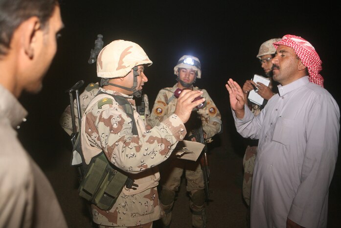 Iraqi Army Capt. Rahim Masin, a platoon commander with 3rd Battalion, 29th Iraqi Army Brigade, converses with a Rutbah, Iraq, citizen at a vehicle check point in western al-Anbar Province, Iraq, Aug. 24. This was the soldiersâ?? first night mission in their new battlespace as they assist Coalition forces and Iraqi Police against insurgent activities and oil smuggling.  The battalion recently assumed control of an area in western al-Anbar province near Rutbah from  2nd Light Armored Reconnaissance Battalion, Regimental Combat Team 5.::r::::n::