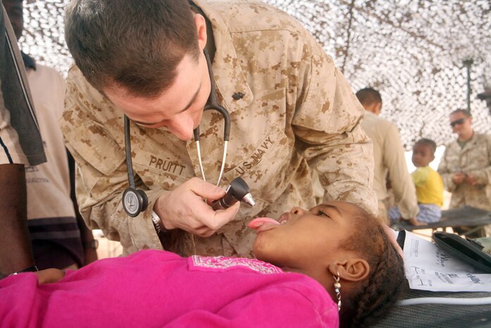 Navy Lt. Michael W. Pruitt, 34, battalion surgeon, 2nd Light Armored Reconnaissance Battalion, Regimental Combat Team 5, examines a 5-year-old Sudanese girlâ??s mouth during a medical engagement in western al-Anbar province, Iraq, Aug. 25. The Sudanese refugees originally came to Baghdad, Iraq, approximately 20 years ago to pursue a better education and occupation to help their families.  For the past three years, they have been living in the desert in tents.  Coalition forces and Iraqi Security Forces make regular visits to check on the refugees.  The community is slated to be relocated to a more established and safer area in the future.