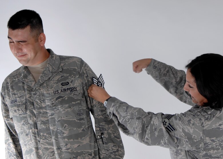 Senior Airman Sonia Vega tacks on her husband, Senior Airman John Vega's new staff sergeant stripes after the promotion results were released Aug. 20.  The Senior Airmen Vegas were high school sweet hearts who have been married for more than four years and have two sons. (U.S. Air Force photo by Airman 1st Class Joanna M. Kresge) 