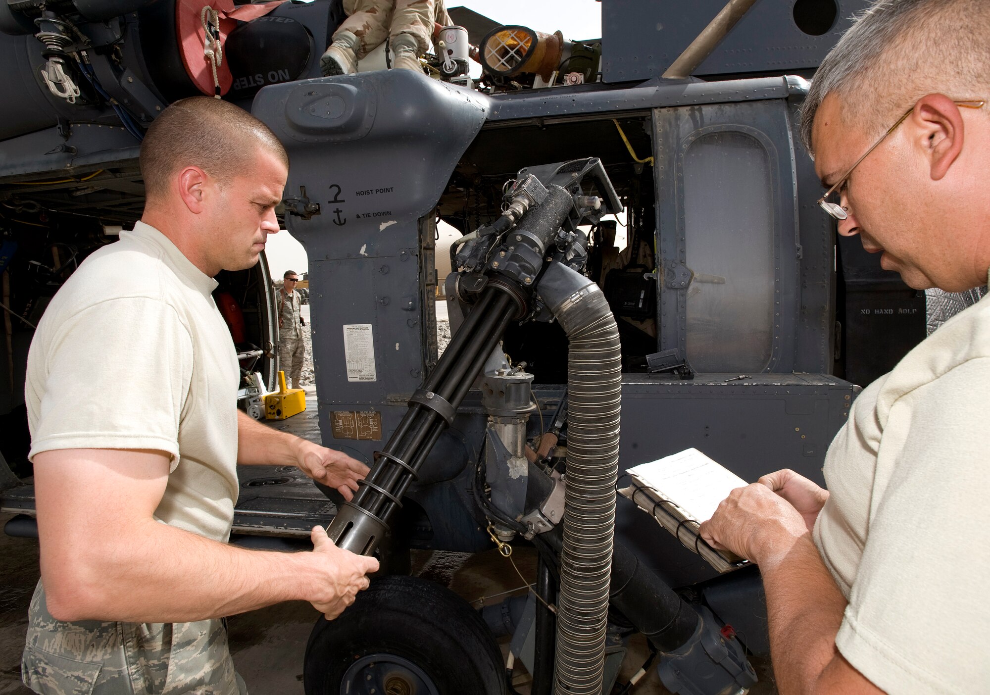 Tech. Sgt. Gary Reinhardt reads from a check list as Tech. Sgt. Mark Christie installs a mini-gun on an HH-60 Pave Hawk prior to a flight Aug. 15 at Kandahar Air Base, Afghanistan. The HH-60 and crews who fly and maintain them are assigned to the 305th Expeditionary Rescue Squadron from Davis-Monthan Air Force Base, Ariz. (U.S. Air Force photo/Master Sgt. Keith Brown) 
