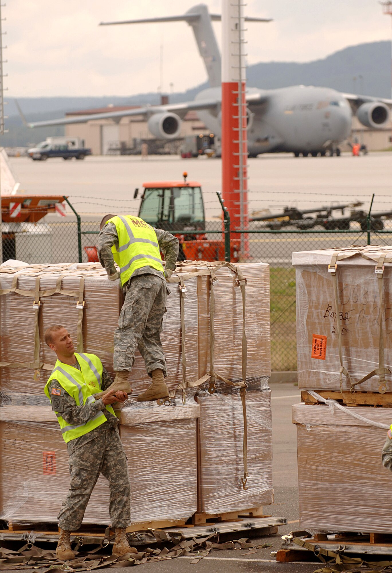 Army Spc. Alexandro Saldana gets a lift from Army Staff Sgt. Jeremiah Wolf before attaching netting to 18 pallets of sleeping bags and cots bound for the Republic of Georgia Aug. 15 at Ramstein Air Base, Germany. The Soldiers are assigned to the 66th Transportation Co., 39th Transportation Battalion based at nearby Kleber Kasserne. (U.S. Air Force photo/Master Sgt. Scott Wagers) 
