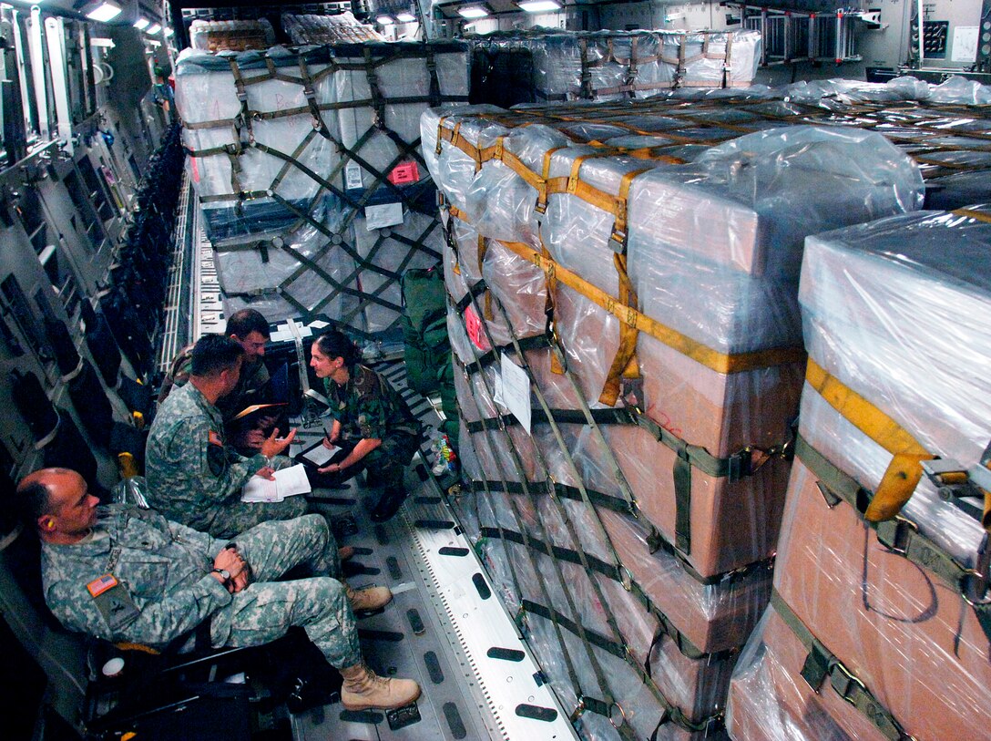 While en route to Tbilisi, Georgia, from Ramstein Air Base, Germany, a small group of Army, Navy and Air Force members discuss details of the joint humanitarian assistance delivery Aug. 13. The delivery consisted of $1 million in U.S.-donated medical supplies, blankets, sleeping bags and bed sheets for the people of the Republic of Georgia. (U.S. Air Force photo/Master Sgt. Scott Wagers) 