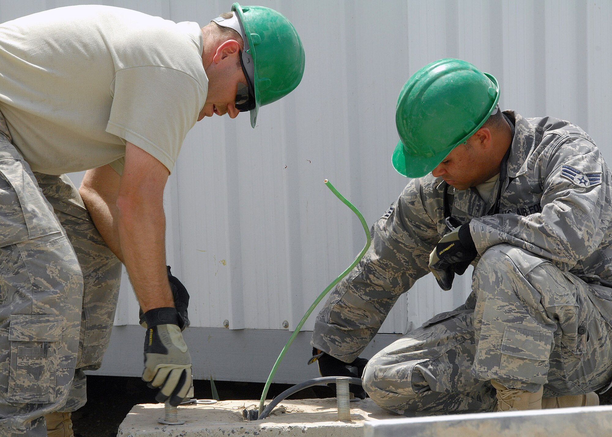 Staff Sgt. Ricky Clark and Senior Airman Jose Lozadacosme tighten down bolts on the base of a light pole on Aug. 23 at an air base in Southwest Asia. They are assigned to the 386th Expeditionary Civil Engineer Squadron.  (U.S. Air Force photo/Tech. Sgt. Raheem Moore) 