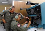 Navy Cmdr. John Radka (left), outgoing 562nd Flying Training Squadron commander, goes over navigation controls with Ens. Joseph Gilligan, a naval flight officer in training, on a T-45 navigation simulator at the 562nd FTS Aug. 21. (U.S. Air Force photo by Rich McFadden)