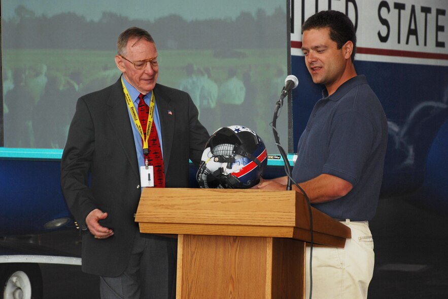 Retired Maj. Gen. Charles Metcalf (left), director of the National Museum of the United States Air Force, accepts hearing protection and communications technology from test pilot Pete Siebold of Scaled Composites, LLC. Mr. Siebold wore the Attenuating Custom Communications Earplug System while piloting a modified Long-EZ aircraft powered by a pulsed-detonation engine developed by the Air Force Research Laboratory’s Propulsion Directorate. (Air Force photo by Chris Gulliford)