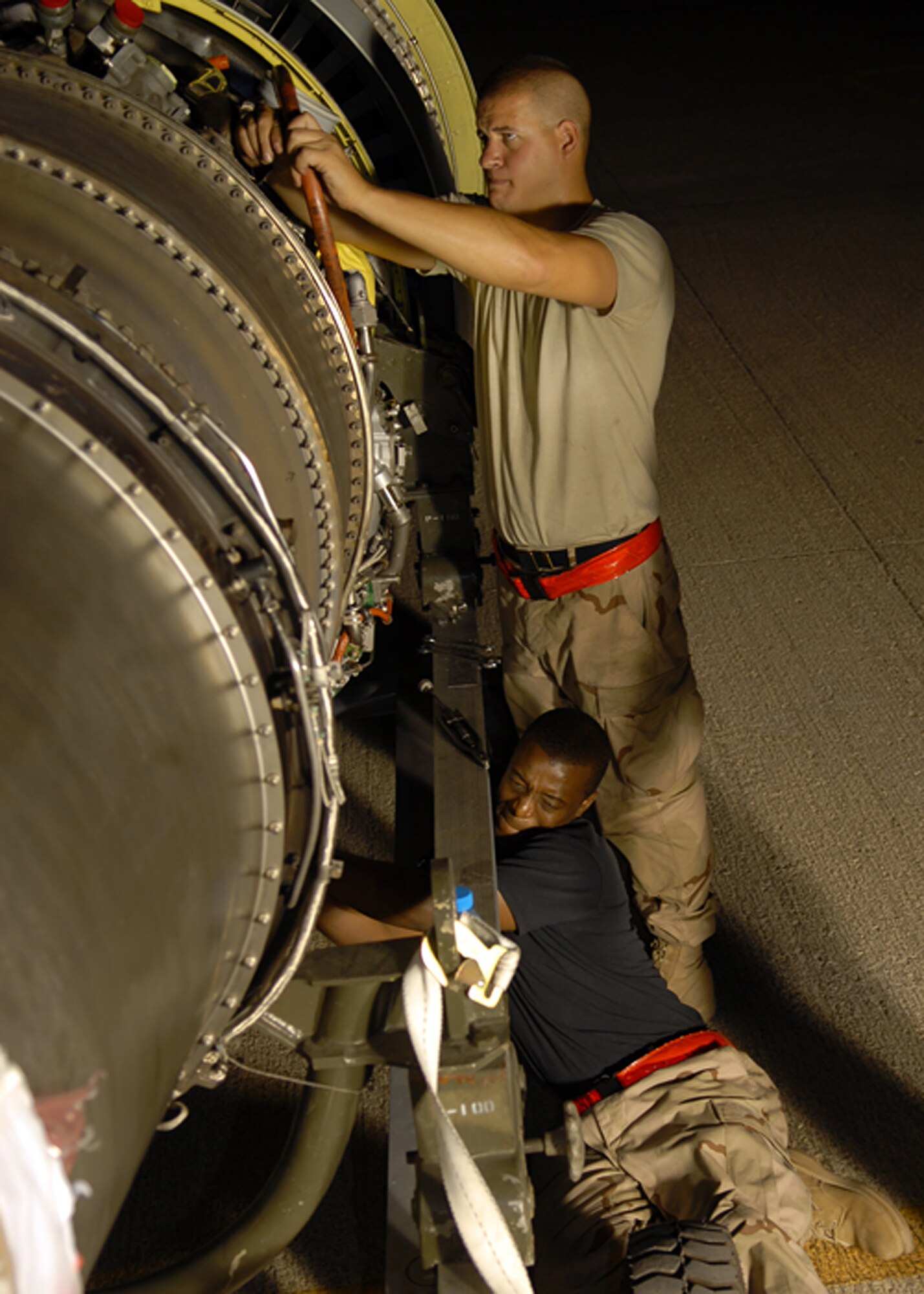 SOUTHWEST ASIA -- Staff Sgt. Bradley Barnes (standing), an engine systems specialist with the 380th Expeditionary Maintenance Squadron, prepares the throttle cable during an engine replacement on an Airborne Warning and Control System aircraft, or E-3 Sentry, here Sunday. Senior Airman Marcus Wilson, 380th EAMXS electro-environmental specialist, assists crew mates on the removal of the hydraulics package. This rotation of 380th EAMXS E-3 maintainers has replaced an unprecedented six engines in 120 days. (U.S. Air Force Photo/Tech. Sgt. Denise Johnson)(released)