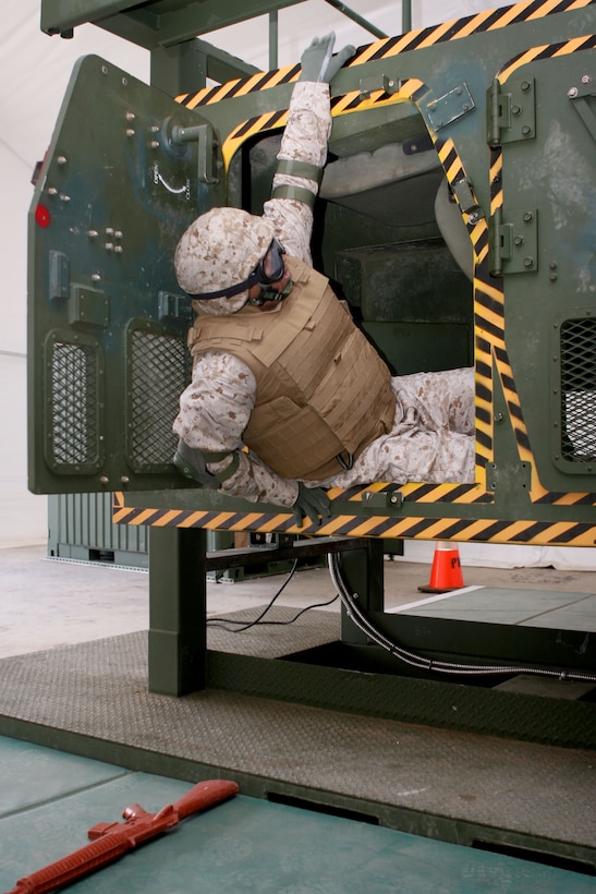Capt. Oronde Dominique, battalion comptroller for Headquarters and Service Battalion, U.S. Marine Corps Forces, Pacific, climbs out of the simulator after it rolled on its roof, during the High-Mobility Multiporpose Wheeled Vehicle Egress Assistance Trainer training Aug. 27 here.
