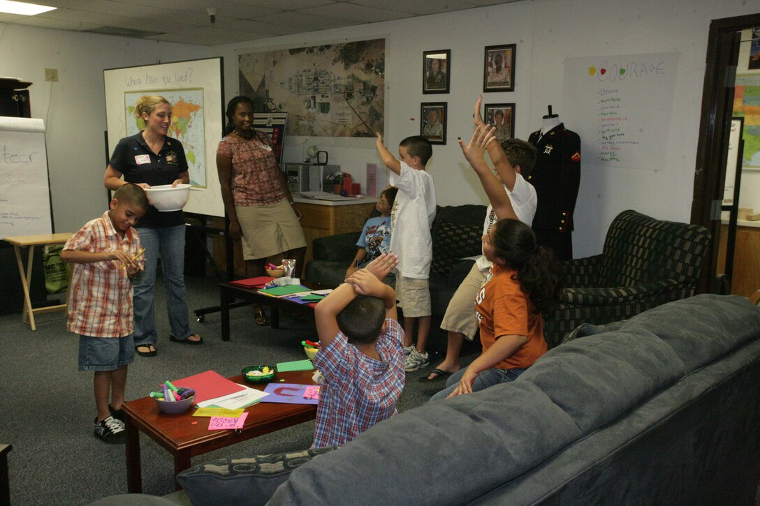 Children stand on their toes and raise their hands for a chance to win a prize after answering a question correctly during the first Kid’s L.I.N.K.S. session at the Kid’s L.I.N.K.S. building Aug. 27.  This was the first L.I.N.K.S. for Kid’s session and marks the beginning of an entirely new series of L.I.N.K.S. programs aimed not only at spouses, but also at children, parents of service members and service members themselves.