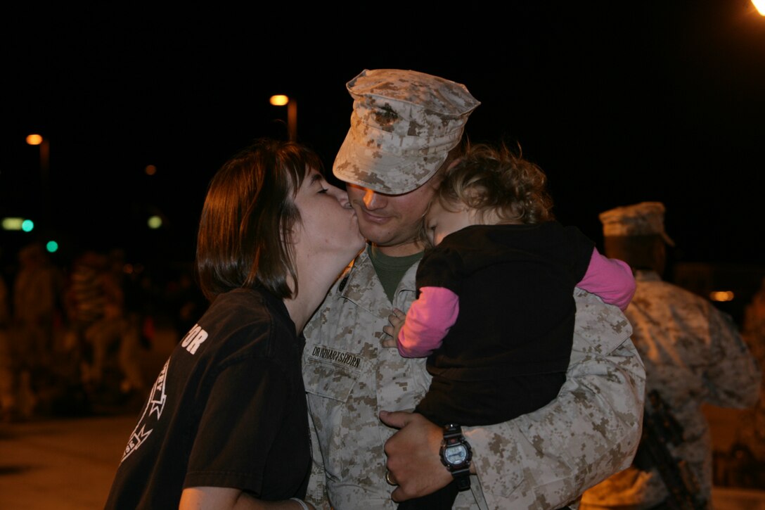 Staff Sgt. Joshua Ortiz, platoon sergeant, Weapons Company, 3rd Battalion, 7th Marine Regiment, receives a kiss from his wife, Chandler, and a hug from daughter, Eliana, at the Combat Center’s Unit Marshalling Area before his departure for Iraq Aug. 27. Marines and sailors from 3/7 departed the Combat Center Aug. 26 and 27 on a seven-month deployment to Iraq in support of Operation Iraqi Freedom.  More than 1,000 Marines and sailors left the Unit Marshalling Area in the early and mid-morning hours of both days to the waves and tears of their families and loved ones.
