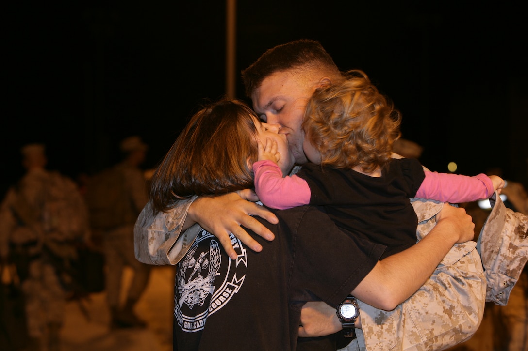 Staff Sgt. Joshua Ortiz, platoon sergeant, Weapons Company, 3rd Battalion, 7th Marine Regiment, receives a kisses from his wife, Chandler, and daughter, Eliana, before leaving for deployment to Iraq at the Combat Center’s Unit Marshalling Area Aug. 27.  Marines and sailors from 3/7 departed the Combat Center Aug. 26 and 27 on a seven-month deployment to Iraq in support of Operation Iraqi Freedom.  More than 1,000 Marines and sailors left the Unit Marshalling Area in the early and mid-morning hours of both days to the waves and tears of their families and loved ones.::r::::n::