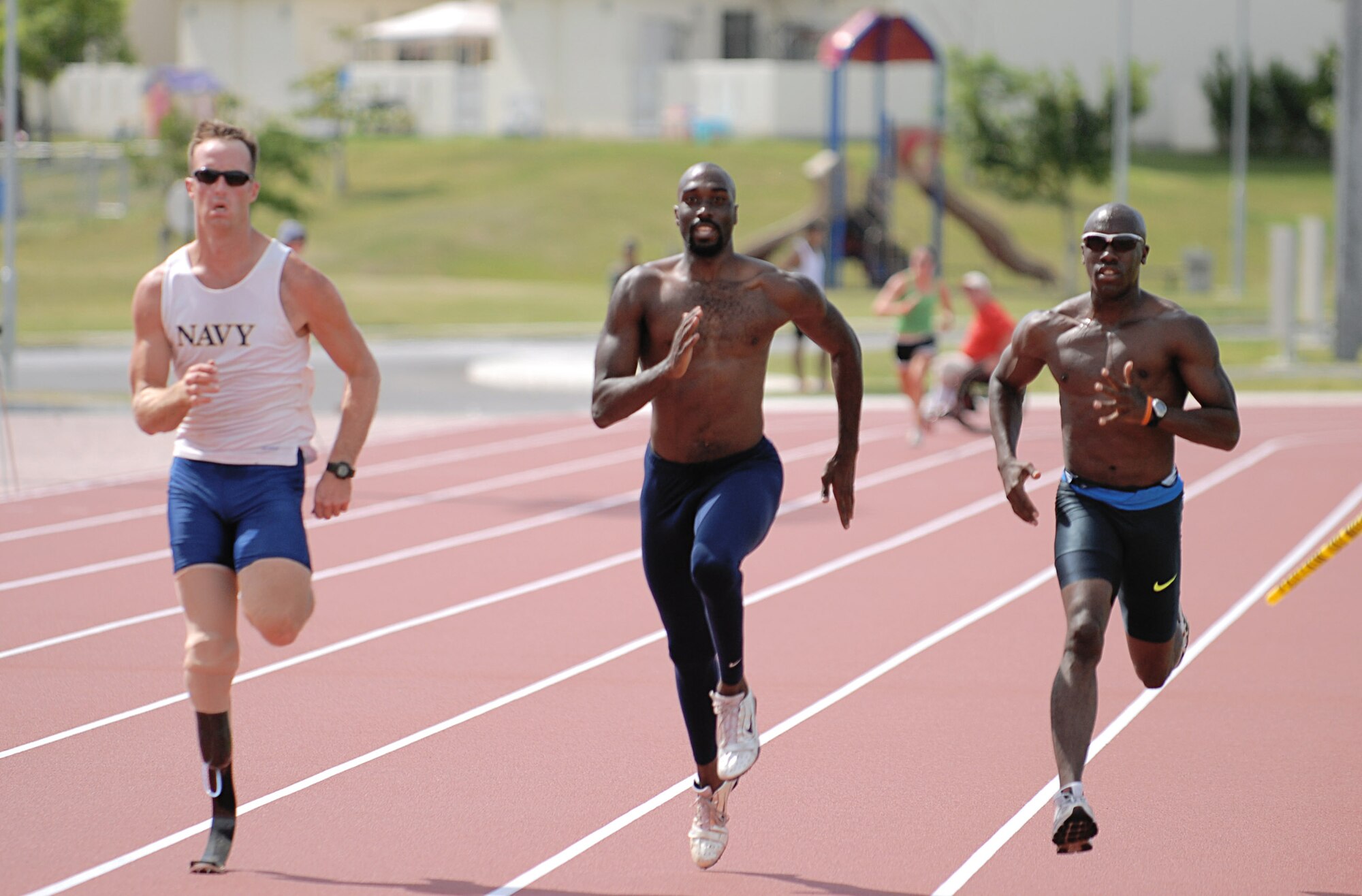 Navy Petty Officer Casey Tibbs(left) from San Diego, Calif., races alongside teammate Josiah Jamison and running guide Jerome Avery, both from Chula Vista, Calif., Aug. 26 at Ryukyu Middle School on Kadena Air Base, Japan.  More than 100 athletes and support staff from the U.S. Paralympics track and field and swim teams arrived on Kadena AB Aug. 24 to live and train for the next ten days in preparation for the 2008 Paralympic Games being held in Beijing, China, Sept. 6. (U.S. Air Force photo/Airman First Class Aaron Johnson)