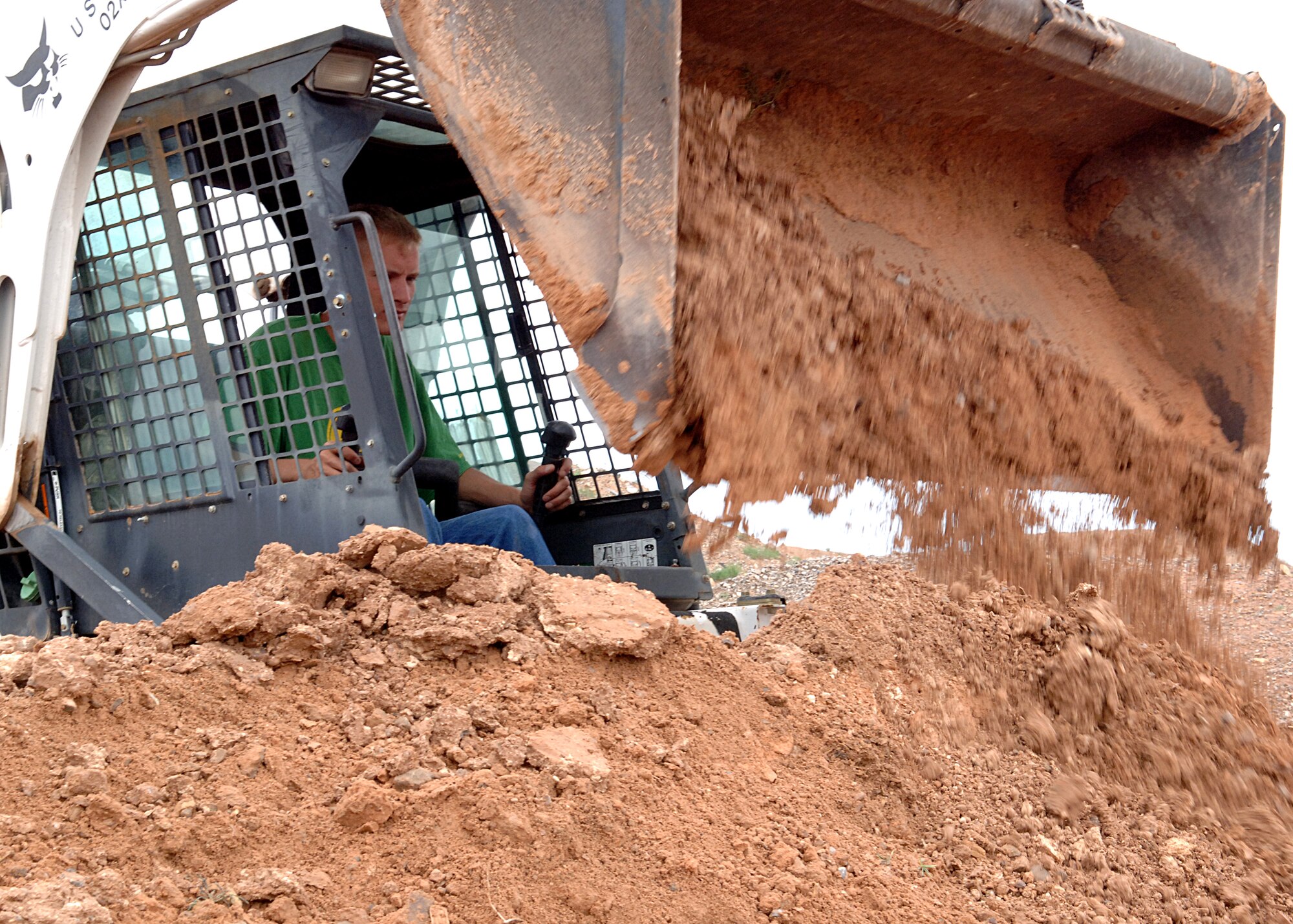 Staff Sgt. Richard Bayer, 49th Civil Engineer Squadron, unloads dirt removed from a curve on the ATV track Aug. 16 at Holloman Air Force Base, N.M.  The heavy repair shop, along with the wing safety office, volunteered to work an early Saturday morning to repair the track.  (U.S. Air Force photo by Airman 1st Class John D. Strong II)