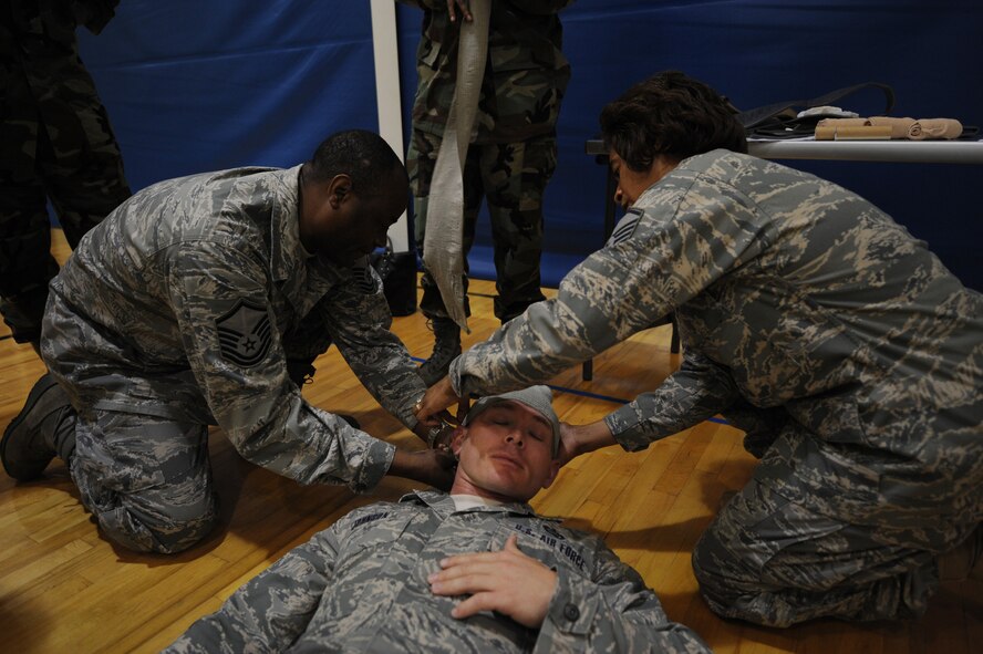 MOODY AIR FORCE BASE, Ga. – Master Sgt. Larry Jackson, 23rd Mission Support Group information management superintendent, left, and Master Sgt. Marsha Prince, 23rd Wing command staff superintendent, right, wrap a mock head injury on Tech. Sgt. Jason Johnson, 23rd Force Support Squadron NCO-in-charge of career support, during self-aid buddy care training here Aug. 26. Airmen received a chance to use items such as bandages, nasalpharyngeals and tourniquets. (U.S. Air Force photo by Senior Airman Gina Chiaverotti)