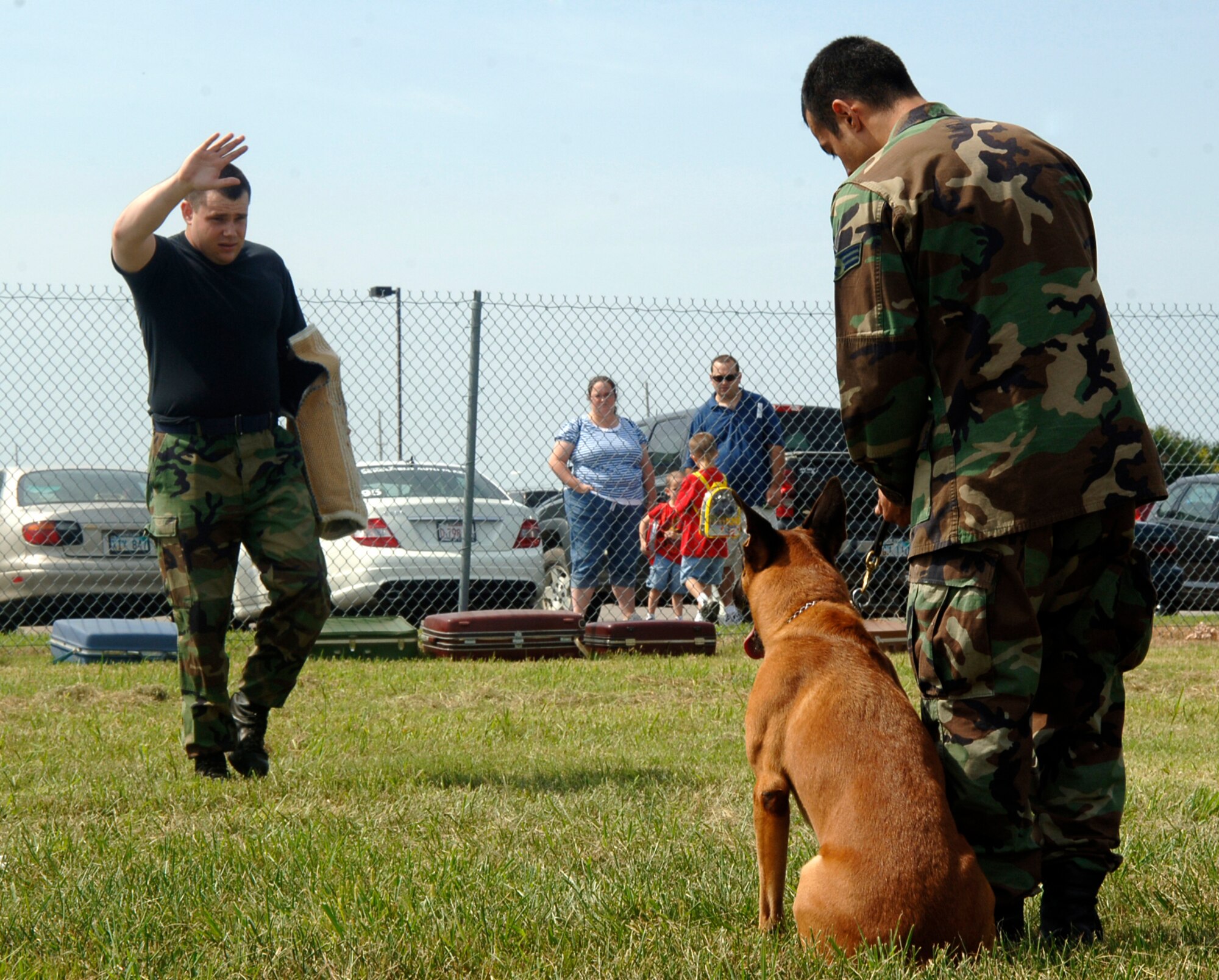 MCCONNELL AIR FORCE BASE, Kan. -- Staff Sgt. Matthew Ellgen approaches Senior Airman Juan Garcia, 22nd Security Forces Squadron, and military working dog, Bram, in a demonstration, at the Colonel James Jabara Airport during the Wichita Flight Festival, Aug. 23. Sergeant Ellgen and his team demonstrate to a crowd how the military working dogs can be friendly but also attack dogs depending on the instruction of their handlers. (Photo by Senior Airman Laura Suttles)