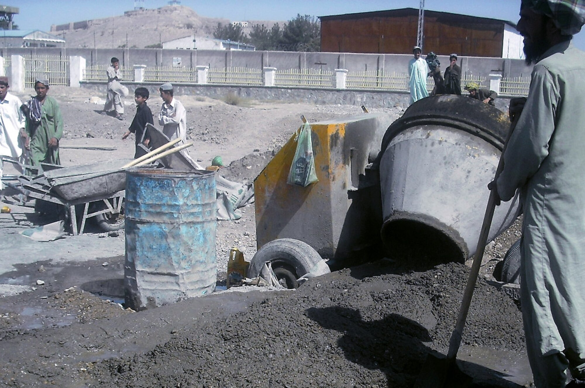 Local contractors mix cement at the Qalat boy's middle and high school campus for the construction of a soccer stadium as students look on Aug. 23 at Qalat, Afghanistan. Members of the Zabul Provincial Reconstruction Team facilitated the installation of a well, electrical upgrade and provided a month of food subsidies for students. Other construction on the grounds includes adding a sewage system to the school complex. (Courtesy photo) 
