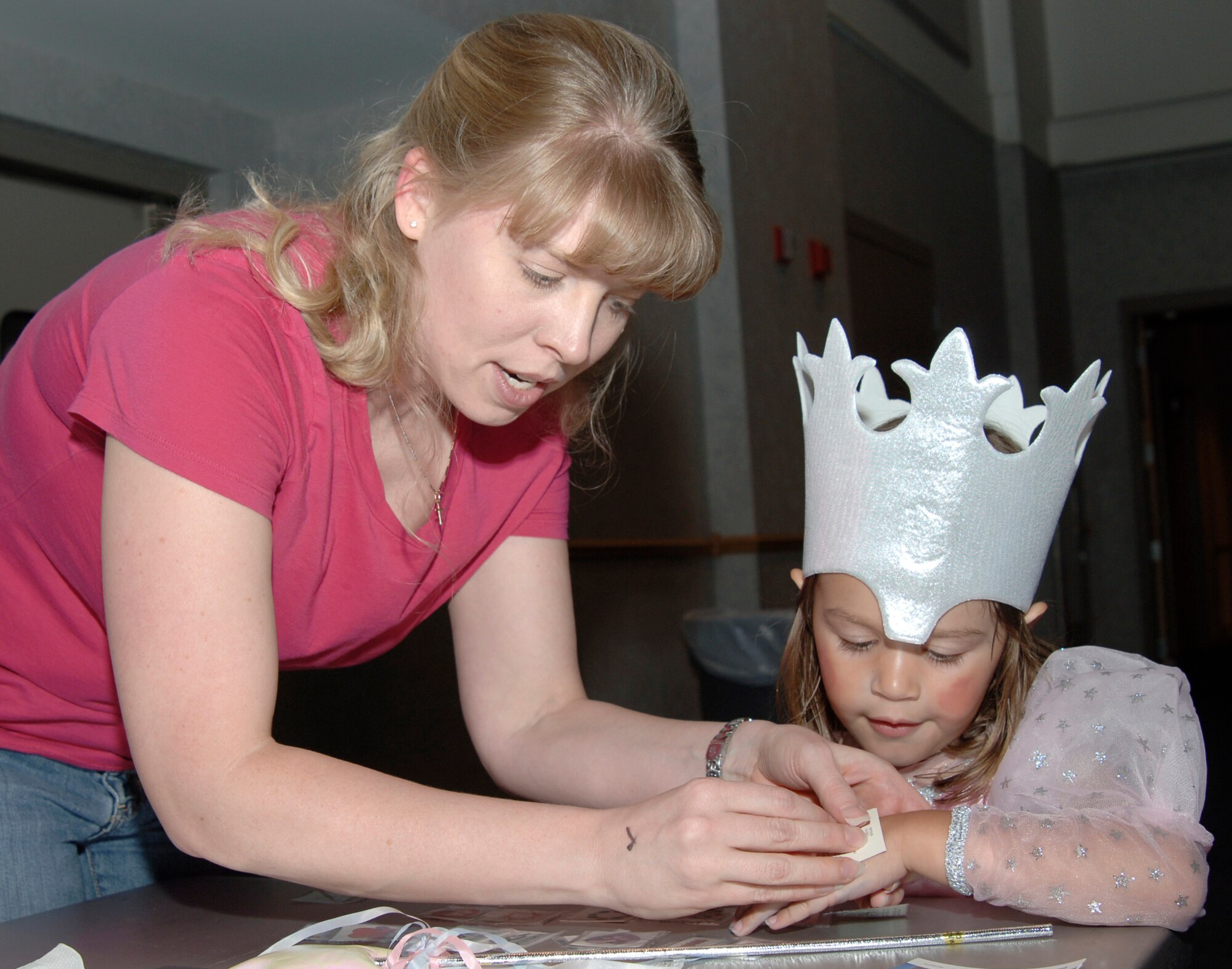 MCCONNELL AIR FORCE BASE, Kan. -- Capt. Tammy Hollister, 22nd Air Refueling Wing, places a fake tattoo on Sarah Morris, 3, daughter of Master Sgt. Anthony Morris, 22nd Maintenance Squadron and Tech. Sgt. Genevieve Morris, 22nd Air Refueling Wing, for the Wizard of Oz Jubilee at the Robert J. Dole Community Center, Aug. 25. The Wizard of Oz Jubilee celebrated the 1939 film release and provided an opportunity for children to play games, eat, dress up and watch the movie. (Photo by Senior Airman Roy Lynch III)