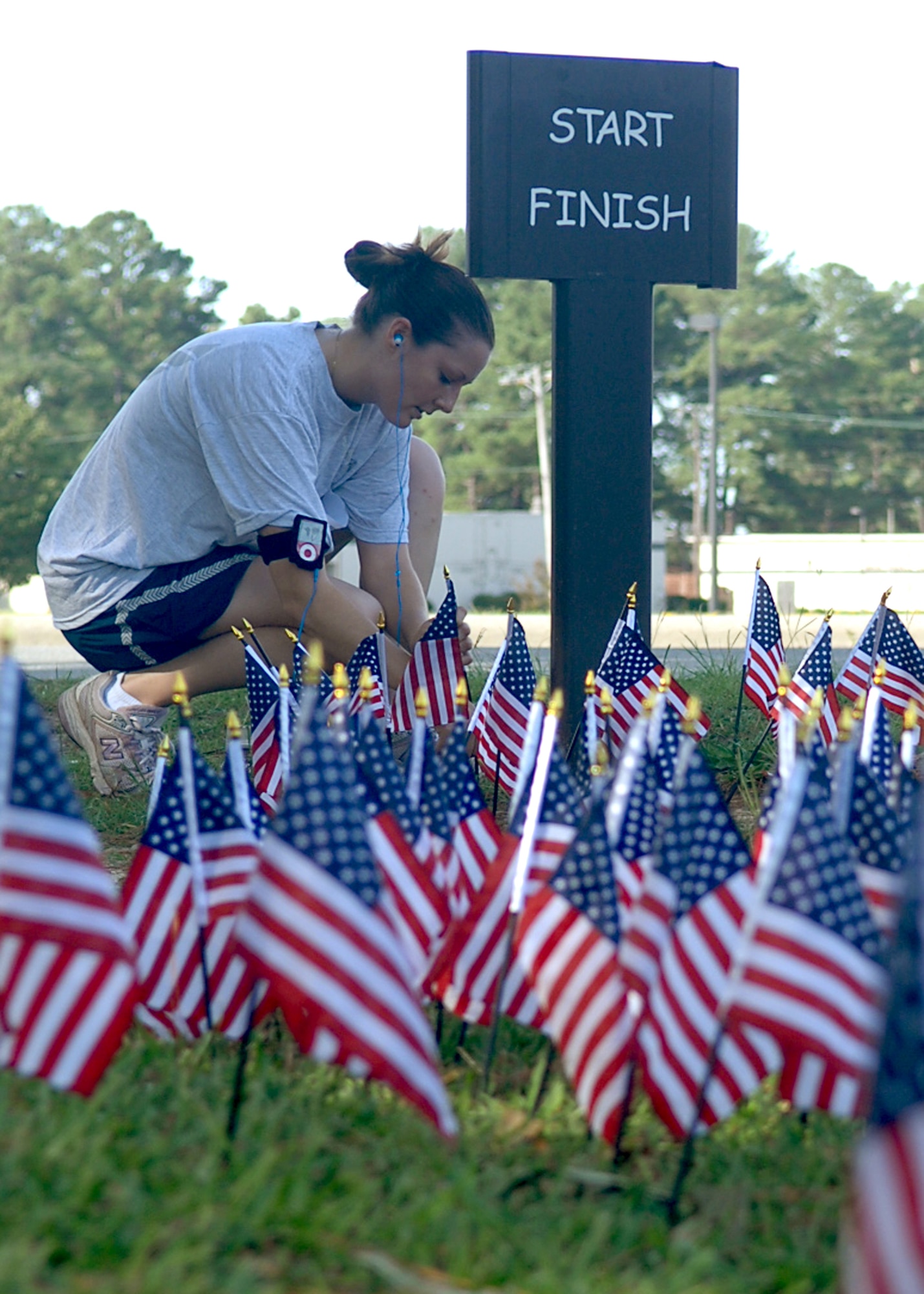 After running two miles as a participant in Run for the Fallen on Seymour Johnson Air Force Base, NC, an Airman places an American flag in the ground in remembrance of fallen military members of Operation Iraqi Freedom and Operation Enduring Freedom, August 24. (U.S. Air Force photo by Airman 1st Class Makenzie Lang)