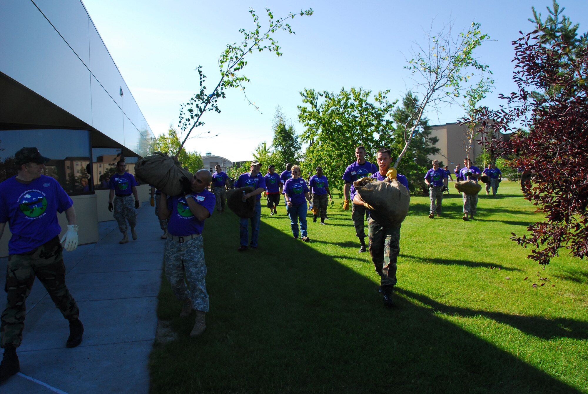 Army, Air Force and civilian volunteers carry trees outside Two Seasons Dining Facility on Eielson Air Force Base as part of Community Partnership Day Aug. 22, 2008. Community Partnership Day enhanced the base this year by planting trees and building new picnic tables. (U.S. Air Force photo/Staff Sgt. Shad Eidson)