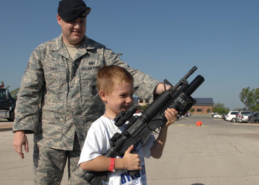 DYESS AIR FORCE BASE, Texas – Staff Sgt. Dorian Davis, 7th Security Forces Squadron, instructs 8 year old Colton Sparks, a military dependent, on how to properly hold an M-4 machine gun that security forces military members may see in a deployment during Operation Dyess Kids, here, 22 Aug.  Operation Dyess Kids is a program that helps dependents of military personnel understand the deployment process on the base.  (U.S. Air Force photo Staff Sergeant Connor Estes).       