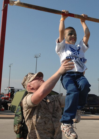 DYESS AIR FORCE BASE, Texas -- Lance Corporal Johsua Crabtree, Detachment 1 Motor Transportation Maintenance Company, assists children do chin ups during Operation Dyess Kids here, 22 Aug.  Operation Dyess Kids is a program that helps dependents of military personnel understand the deployment process on the base.  (U.S. Air Force photo Staff Sergeant Connor Estes).      