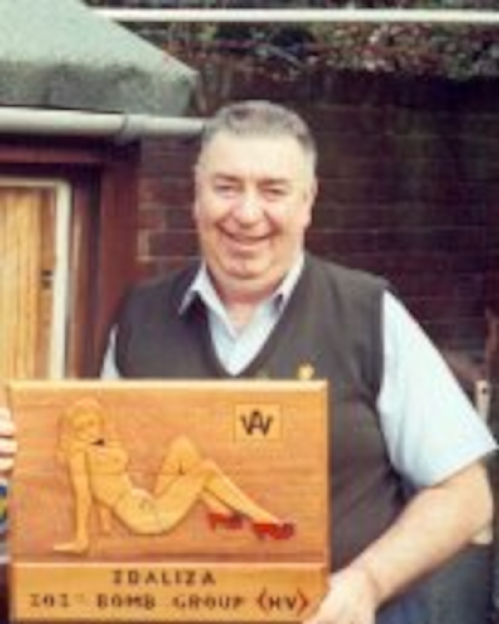 Master Wood Carver William F. Bill Adams displays one of his wood carvings now on display at the JIOCEUR Analytic Center at RAF Molesworth.  Mr. Adams who as a scared young boy was comforted by an American pilot during a WWII bomb raid, created over 500 carvings displayed around the world.  (Photo courtesy 303rd Bomb Group Association)