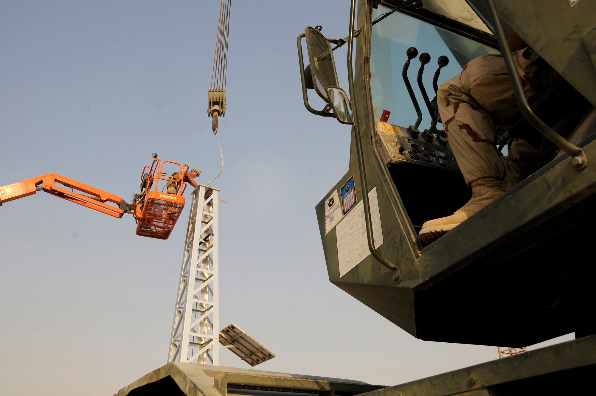 Airman 1st Class Joshua Slaughter, 379th Civil Engineer Squadron, disconnects a strap that was used to connect a new tower to the crane Aug. 26, 2008, at an undisclosed air base in Southwest Asia. Airman Slaughter working from a man lift works from a height even with the top of the tower to loosen and remove the strap. Airman Slaughter along with Senior Airman Kyle Troxell, 379 ECES, are members of a team exchanging aging towers with a sturdier replacement that should last nearly twice as long.  The Giant Voice system is used to communicate important information to all base populace instantaneously.  Airman Slaughter, a native of Eagle, Neb., is deployed from Travis Air Force Base, Calif. Airman Troxell is deployed from Scott Air Force Base, Ill. Both are deployed in support of Operations Iraqi and Enduring Freedom and Joint Task Force-Horn of Africa.  (U.S. Air Force photo by Tech. Sgt. Michael Boquette/Released)