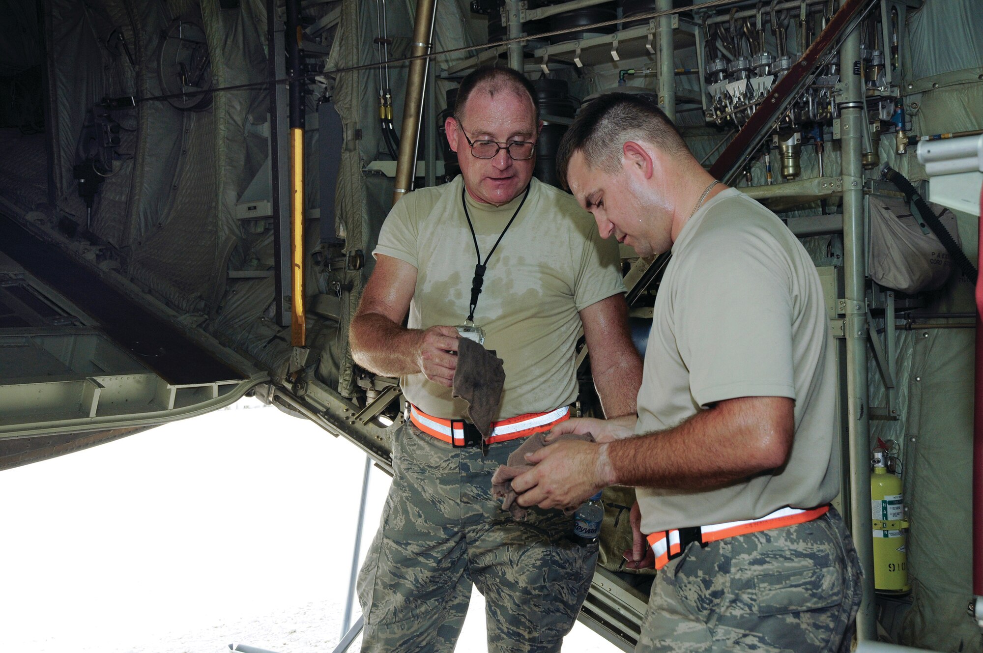 Tech. Sgt. Sidney J. Wolfe starts packing up cleaning rags as he is handed another by his father, Tech. Sgt. Sidney R. Wolfe Aug. 21, 2008, at an undisclosed location in Southwest Asia.  Both Airmen, assigned to the 379th Expeditionary Aircraft Maintenance Squadron, 55th Aircraft Maintenance Unit, are deployed from the Youngstown Air Reserve Station, Ohio.  Tech. Sgt. Sidney J. Wolfe resides in Salem, Ohio, while his father, Sidney R. Wolfe hails from Hanover, Ohio. Both are supporting Operations Iraqi and Enduring Freedom and Joint Task Force-Horn of Africa. (U.S. Air Force photo by Tech. Sgt. Michael Boquette/Released)