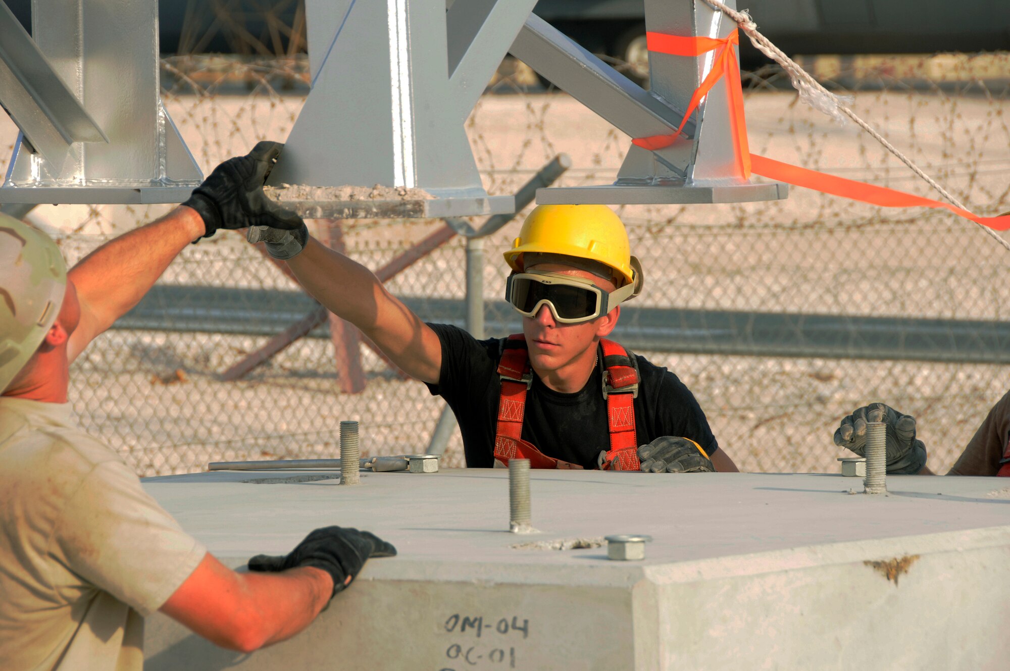 Tech. Sgt. Camon Tucker, 379th Expeditionary Civil Engineer Squadron, and Staff Sgt. Jonathan Arnold, 379th Expeditionary Communications Squadron, guide the tower down toward bolts embedded in a concrete base Aug. 26, 2008, at an undisclosed location in Southwest Asia.  Sergeants Tucker and Arnold are members of a team exchanging aging towers with a sturdier replacement that should last nearly twice as long.  The Giant Voice system is used to communicate important information to all base populace instantaneously. Sergeant Tucker is deployed from F.E. Warren Air Force Base, Wyo. Sergeant Arnold, a native of Muncie, Ind., is deployed from the Fort Wayne Air National Guard, Ind.  Both are deployed in support of Operations Iraqi and Enduring Freedom and Joint Task Force-Horn of Africa.  (U.S. Air Force photo by Tech. Sgt. Michael Boquette/Released)