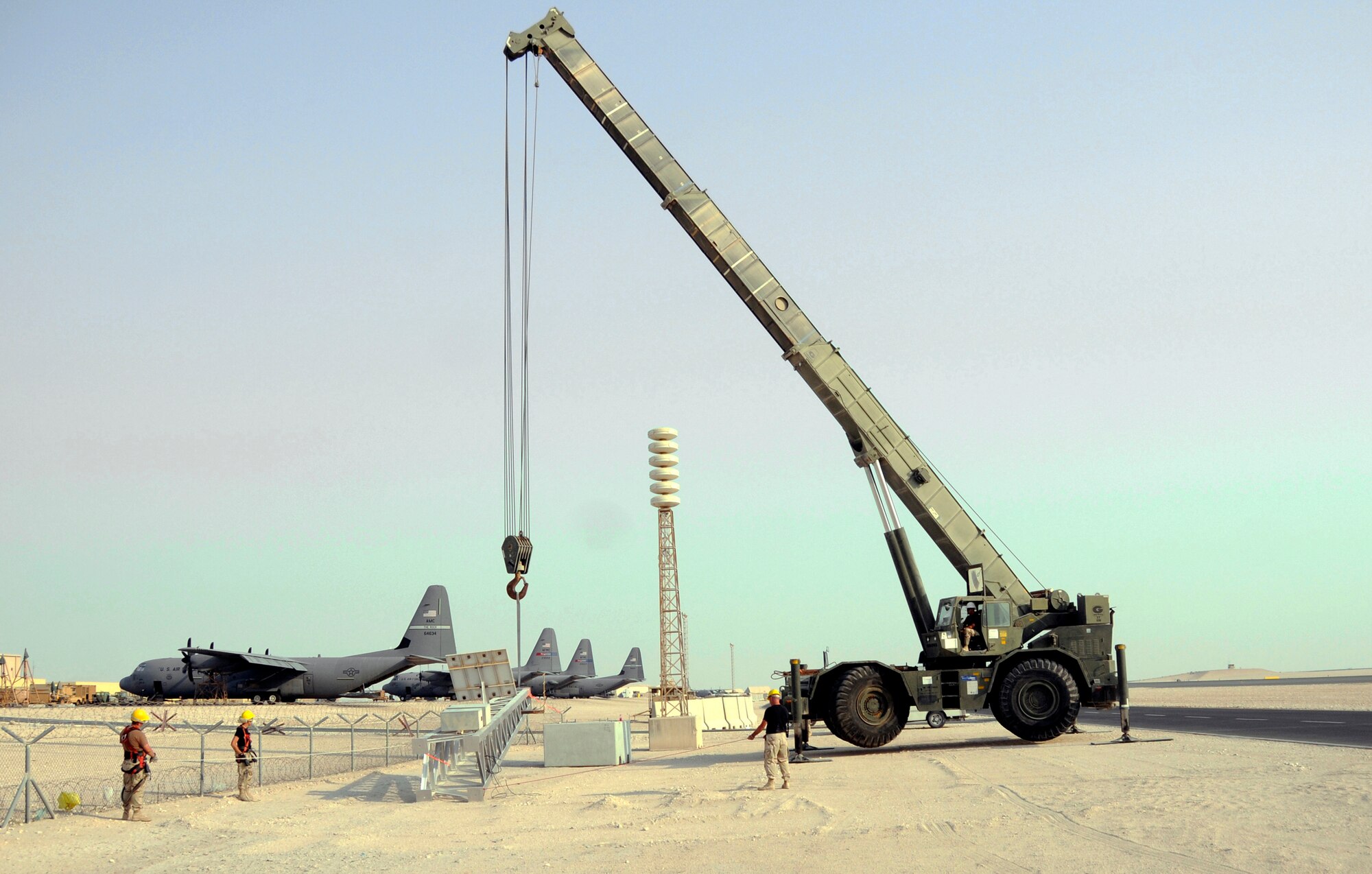 Senior Airman Kyle Troxell, 379th Expeditionary Civil Engineer Squadron, operates a 60-ton crane efficiently lifting a new Giant Voice tower onto its cement block mount Aug. 26, 2008, at an undisclosed location in Southwest Asia. Senior Airman Clinton Rowland, 379th Expeditionary Communications Squadron, holds a rope attached to the top left leg of the tower, while Staff Sgt. Clyde Hunt, 379 ECS, holds a line attached to the tower’s bottom right leg.  The ropes are used as guides to keep the tower in line once in the air.  Sergeant Hunt, Airman Rowland and Airman Troxell are members of a team exchanging aging towers with a sturdier replacement that should last nearly twice as long.  The Giant Voice system is used to communicate important information to all the base population instantaneously. Sergeant Hunt, a native of Shreveport La., is deployed from the Louisiana Air National Guard. Airman Rowland hails from Athens, Ga., and is deployed from Royal Air Force Lakenheath, United Kingdom. Airman Troxell is deployed from Scott Air Force Base, Ill.  All are supporting Operations Iraqi and Enduring Freedom and Joint Task Force-Horn of Africa.  (U.S. Air Force photo by Tech. Sgt. Michael Boquette/Released)