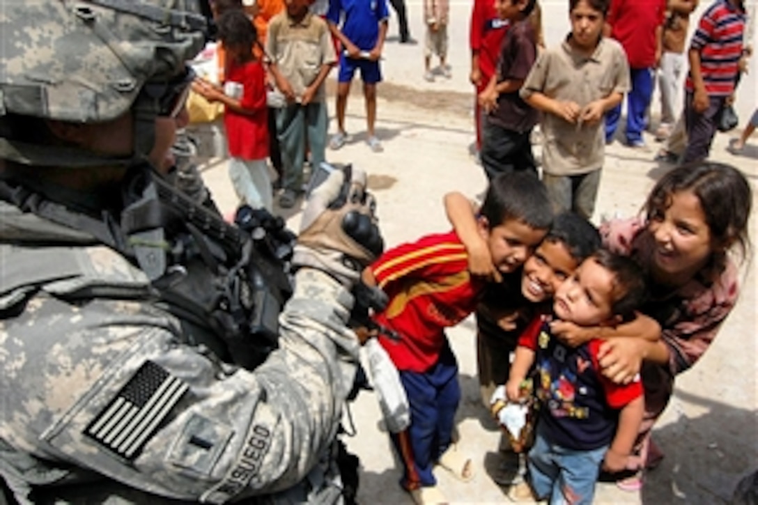 U.S. Army 1st Lt. John Busuego photographs a small group of children in Baghdad,  Iraq, Aug. 19, 2008. Busuego is the economics development coordinator for the 25th Infantry Division's 1st Battalion, 27th Infantry Regiment.