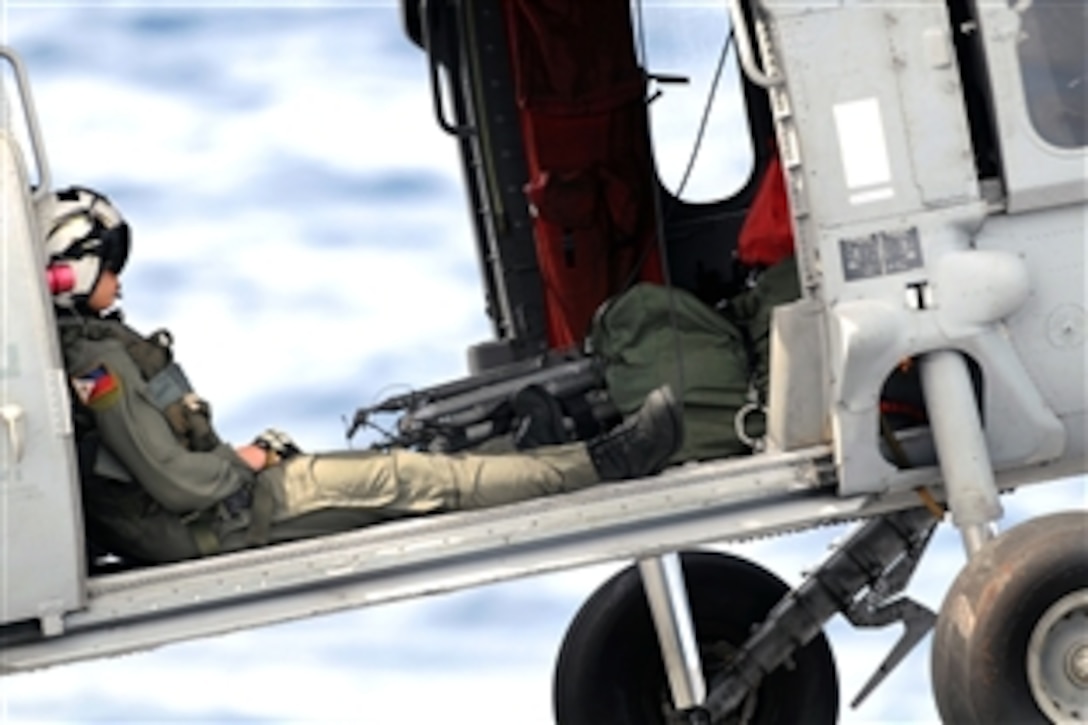 A U.S. Navy aircrewman sits in a Knight Hawk helicopter as it lifts off the aircraft carrier USS Ronald Reagan during a replenishment at sea with the Military Sealift Command ship USNS Bridge while under way in the Indian Ocean, Aug. 23, 2008. 