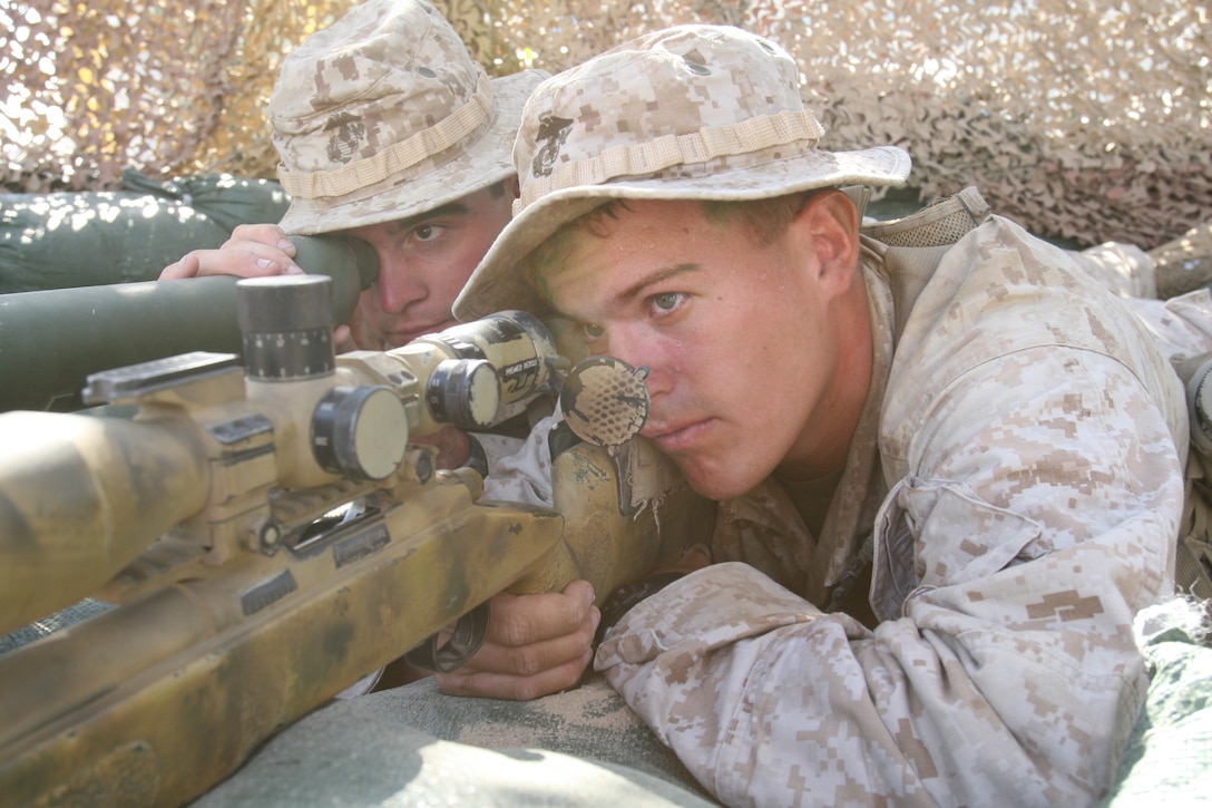 Lance Cpl. Daniel Hillin, a scout with Scout Sniper Platoon, 1st Battalion, 7th Marine Regiment, and Lance Cpl. Brandon Padilla, his spotter, show how a sniper and spotter work together to select and engage a target outside the 7th Marines armory at the Combat Center Aug. 28, 2008.