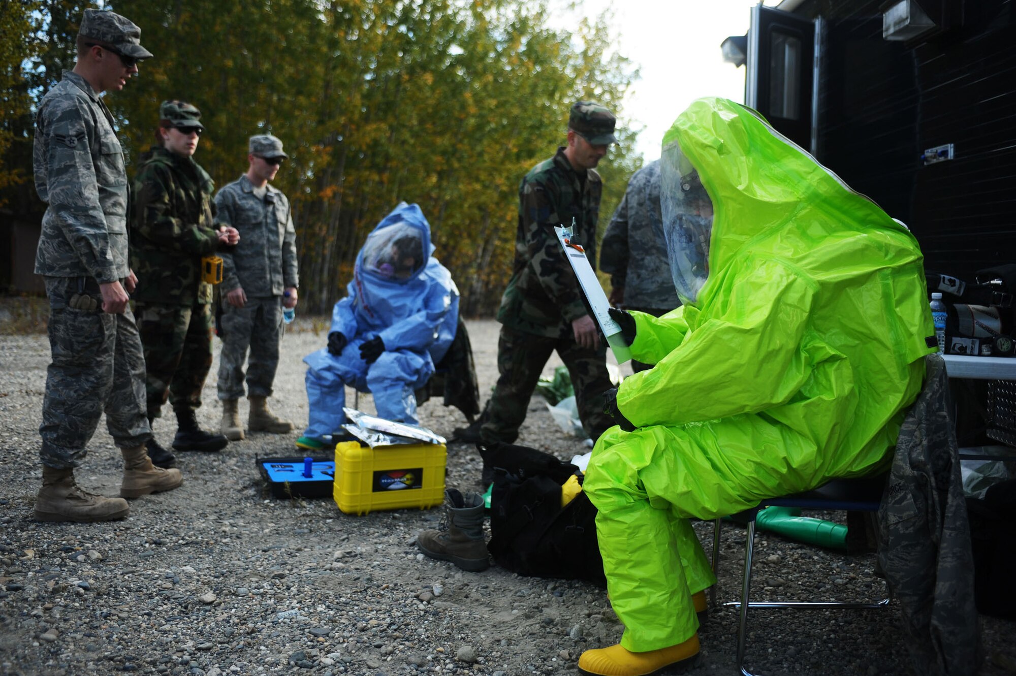 Staff Sgt. Michael Huntington, right, looks over his paperwork as his co-workers suit up and gather equipment prior to leaving for the contamination site Aug. 28, 2008, at Eielson Air Force Base, Alaska. Airmen of the 354th Civil Engineer Squadron readiness flight conducted a training exercise to respond to an improvised explosive device with a white, powdered substance attached to it. This exercise helps them maintain their certification and gain experience on handling this type of situation. Sergeant Huntington is assigned to the 354th CES readiness flight.  (U.S. Air Force photo by Airman 1st Class Jonathan Snyder)