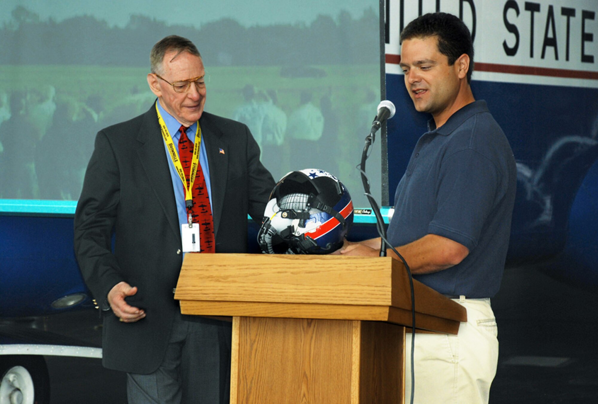 Retired Maj. Gen. Charles Metcalf (left), director of the National Museum of the United States Air Force, accepts hearing protection and communications technology from test pilot Pete Siebold of Scaled Composites, LLC. Mr. Siebold wore the Attenuating Custom Communications Earplug System while piloting a modified Long-EZ aircraft powered by a pulsed-detonation engine developed by the Air Force Research Laboratory's Propulsion Directorate. (Air Force photo by Chris Gulliford) 
