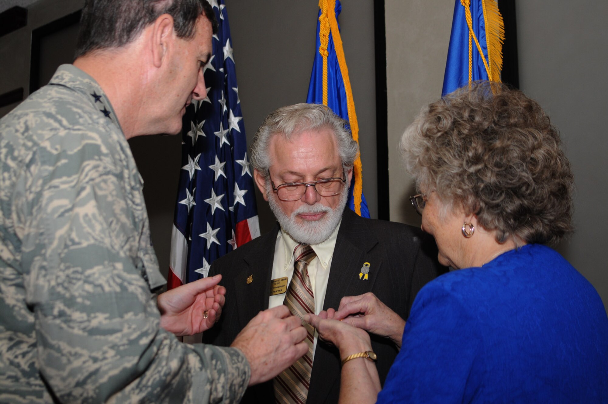 Gen. Stephen Lorenz, left, commander of Air Education and Training Command, presents Werner Lamm a pin recognizing his 50 years of federal service.  The general is assisted by Mr. Lamm’s wife, Barbara Ann.  Mr. Lamm is the 338th Training Squadron’s training support chief. The presentation was made Aug. 21 in Stennis Hall.  (U.S. Air Force photo by Kemberly Groue)