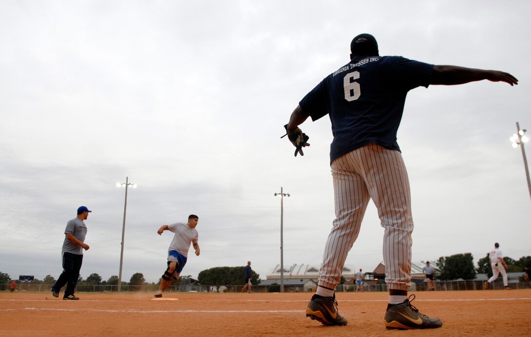 LANGLEY AIR FORCE BASE, Va. -- An Airman of the 480th Intelligence Wing signals Senior Airman Ricardo Hernandez to home plate during a softball playoff game between the 480th Intelligence Wing and 1st Communications Squadron.  The 1st CS defeated the 480th IW 19-7 as the Langley softball season comes to a close and prepares for final eliminations this week.  (U.S. Air Force photo/Senior Airman Vernon Young)