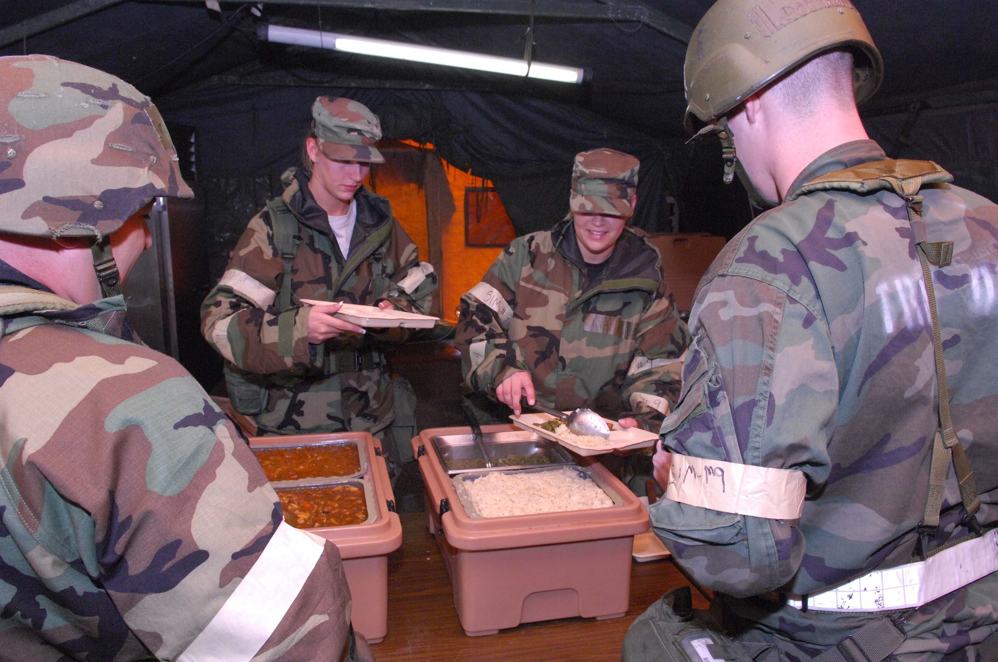 SHAW AIR FORCE BASE, S.C. -- Senior Airman Tiffany Cole and Airman 1st Class  Anna Reece, 20th Services Squadron, serve hot meals in a field kitchen to Master Sgt. David Sinay and 1st Lt. Daniel Connors, 20th Equipment Maintenance Squadron, during a Phase II Operational Readiness Exercise Aug. 27. OREs provide vital training and prepare Airmen for worldwide deployment. (U.S. Air Force photo/Senior Airman William Coleman)