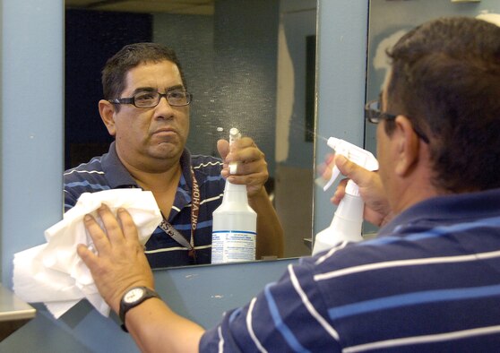 Lee  Johnson, a janitor with Dale Rogers Training Center, cleans a restroom in the Bldg. 3001 maintenance area.   Areas cleaned and their frequency will change as budgets are tightening for custodial, grounds maintenance and trash collection contracts. (Air Force photo/Margo Wright)
