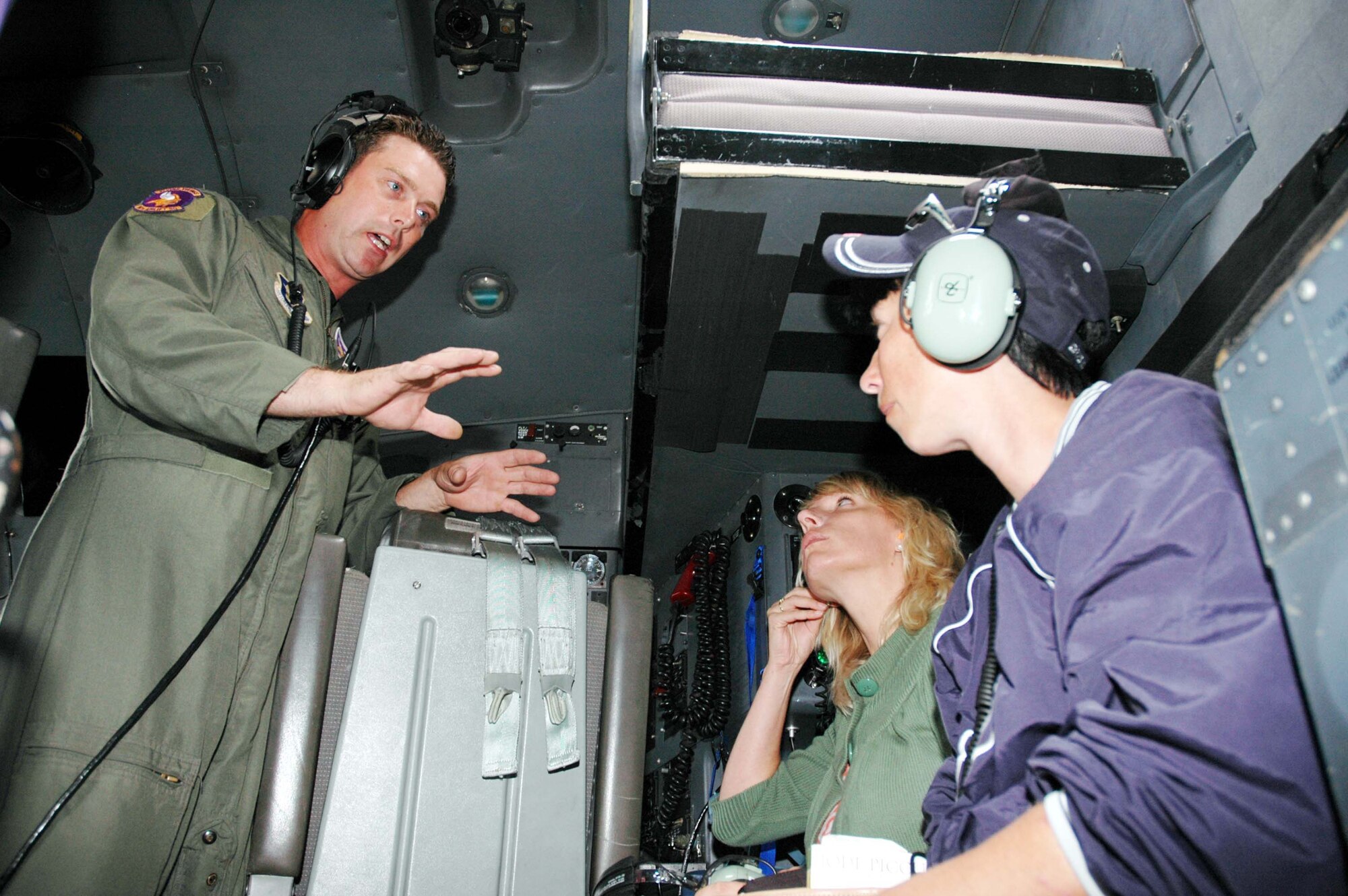 Capt. Mitchell Maes, 934th Operations Support Flight, explains headphone use to Tammy Hauer (right), wife of Robert Hauer, 27 APS, and Teresa Rettman, wife of Ben Rettman, 934 AMXS during a Spouse Flight on Sunday of the August UTA. (Air Force Photo/Tech. Sgt. Jeff Williams) 